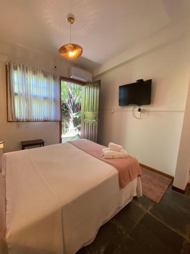 a bedroom with a bed and a tv and a window at Hospedagem Tulipane - Praia do Campeche in Florianópolis