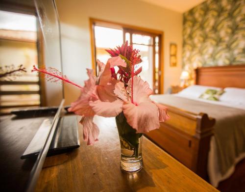 a vase with pink flowers on a table in a bedroom at Hospedagem Tulipane - Praia do Campeche in Florianópolis