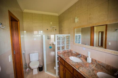 a bathroom with a sink and a shower and a toilet at Hospedagem Tulipane - Praia do Campeche in Florianópolis