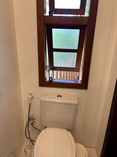 a bathroom with a toilet and a window at Hospedagem Tulipane - Praia do Campeche in Florianópolis