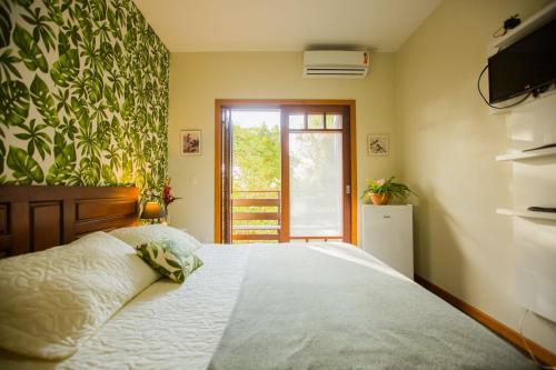 a bedroom with a bed and a television and a window at Hospedagem Tulipane - Praia do Campeche in Florianópolis