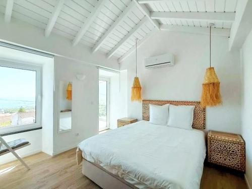 une chambre blanche avec un lit et une grande fenêtre dans l'établissement Casa dos Castanheiros - The White Cottage, à Canto da Areia