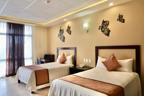 una camera d'albergo con due letti e farfalle sul muro di Hotel Yorio Inn a Tuxpan de Rodríguez Cano