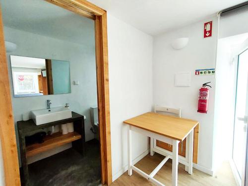 La salle de bains est pourvue d'un lavabo, d'un miroir et d'une table. dans l'établissement Casa dos Castanheiros - The White Cottage, à Canto da Areia
