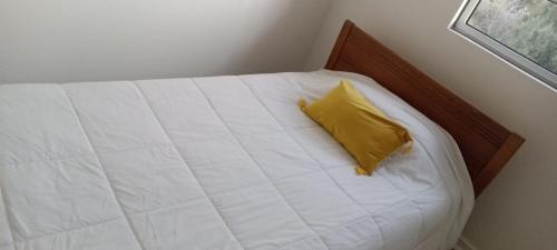 a white bed with a yellow pillow on it at Los Olivos 404 B in Vallenar