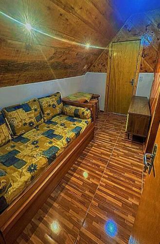 a bedroom with a couch and a wooden floor at Chalé Sossego 3 in Campos do Jordão