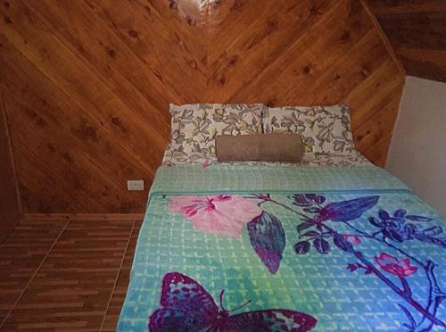 a bed with a colorful bedspread with butterflies on it at Chalé Sossego 3 in Campos do Jordão