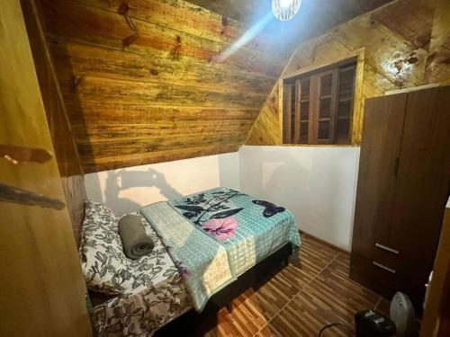 a small bedroom with a bed in a wooden room at Chalé Sossego 3 in Campos do Jordão