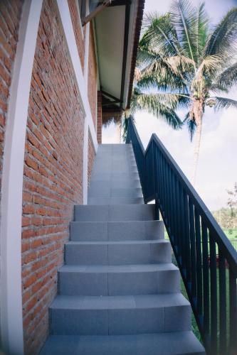 a staircase leading up to a brick building with a palm tree at Novia Guest House Lombok-Tetebatu in Tetebatu