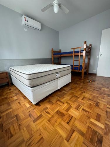 a bedroom with a bed and a wooden floor at Vista Maravilhosa Pitangueiras in Guarujá