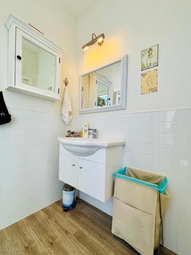 a white bathroom with a sink and a mirror at Papanui Paris inspired Apartment in Christchurch