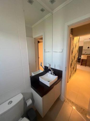 a bathroom with a sink and a toilet and a mirror at Cobertura 402- 2 Dormitórios Praia de Bombas in Bombas