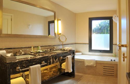 a bathroom with a sink and a tub and a large mirror at Iguazú Grand Resort Spa & Casino in Puerto Iguazú