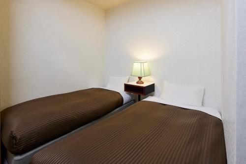 two beds in a room with a lamp on a table at Kamenoi Hotel Aso Park Resort in Aso
