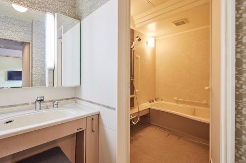 a bathroom with a sink and a bath tub at Kamenoi Hotel Aso Park Resort in Aso