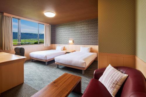 a hotel room with two beds and a table at Kamenoi Hotel Aso Park Resort in Aso