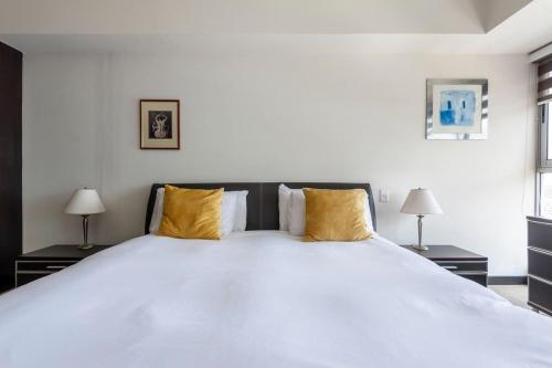 a bedroom with a large white bed with yellow pillows at Beautiful apartment w/amenities in front of CARSO in Mexico City