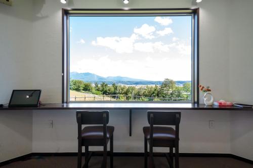 une fenêtre avec deux chaises devant un bureau avec un ordinateur portable dans l'établissement The Kokage, à Nakafurano