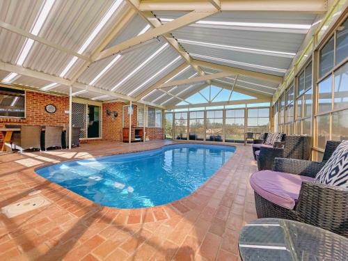 a large swimming pool in a large room with windows at Nottage Cottage in Branxton