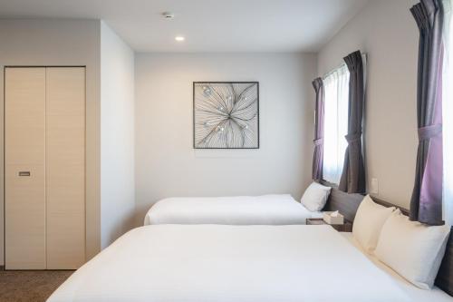two beds in a room with white walls at Elite Inn Kyoto Station エリートイン京都駅 in Kyoto