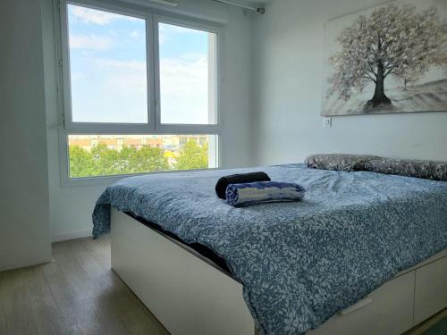 une chambre avec un lit avec une couette bleue et une fenêtre dans l'établissement Le Senghor, Évry-Courcouronnes