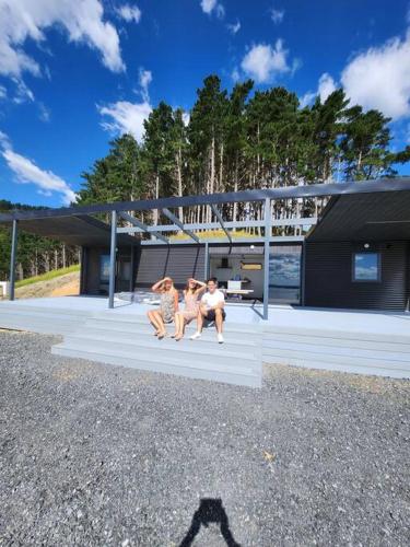 three people sitting on the front porch of a house at Romantic Countryside Lakeview, 1 hour ex Auckland in Waiterimu