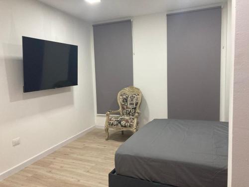 a bedroom with a bed and a chair and a flat screen tv at 2325 Apartaestudios in Arauca
