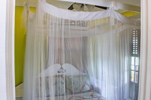Un dormitorio con una cama con dosel y cortinas blancas. en Montete Cottages, en Choiseul