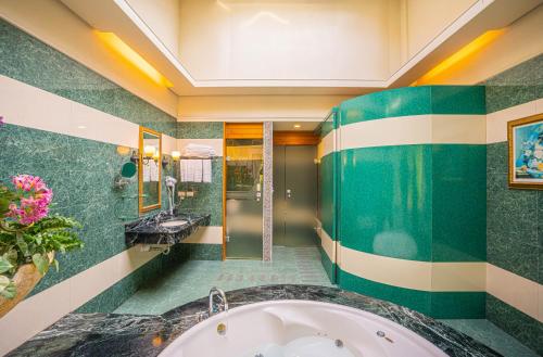 a bathroom with a tub and green tiles at Regale Motel in Zhonghe