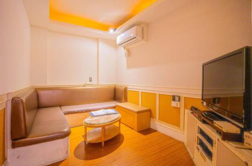 a living room with a couch and a flat screen tv at Regale Motel in Zhonghe