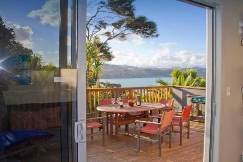 a table and chairs on a balcony with a view of the ocean at Orca Lodge in Raglan