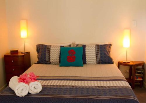 a bedroom with a bed with towels and two lamps at Orca Lodge in Raglan