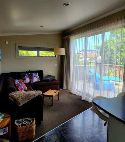 a living room with a couch and a large window at Orca Lodge in Raglan
