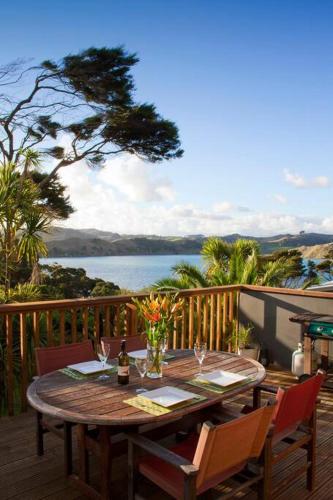 a wooden deck with a table with wine glasses on it at Orca Lodge in Raglan