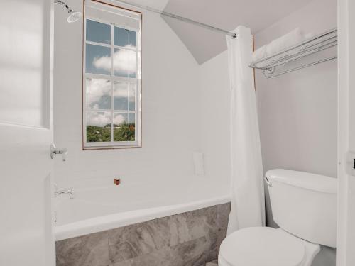 a white bathroom with a toilet and a window at Valentines Resort & Marina in Harbour Island