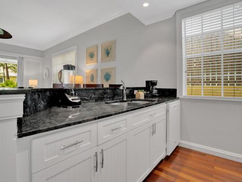 a kitchen with white cabinets and a black counter top at Valentines Resort & Marina in Harbour Island