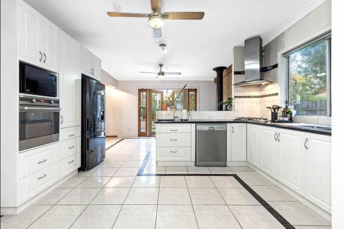 a large kitchen with white cabinets and appliances at Pet Friendly Cottage on Large Sunny Block & 5 mins-CBD in Canadian