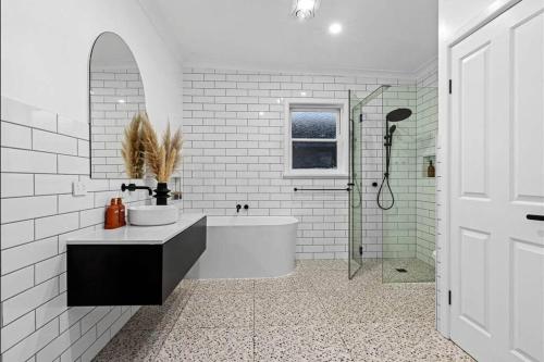 a white bathroom with a tub and a sink at Pet Friendly Cottage on Large Sunny Block & 5 mins-CBD in Canadian