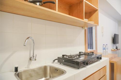 a kitchen with a stove and a sink at Cozy and Simply Look Studio Tokyo Riverside PIK 2 Apartment By Travelio in Rawalembang
