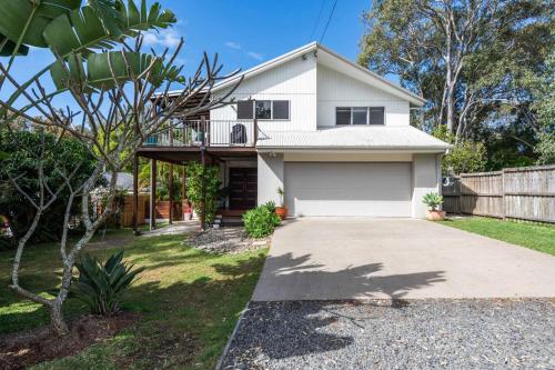ein weißes Haus mit einer Einfahrt und einem Zaun in der Unterkunft Casa Del Lago - Oceanstays - Lakehouse in Yamba