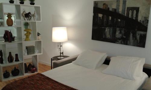 a bedroom with a white bed and a lamp and shelves at Beautiful Studio in Historic Alfama in Lisbon