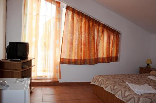 a bedroom with a bed and a television and a window at Vila Bucura 19 A in Venus