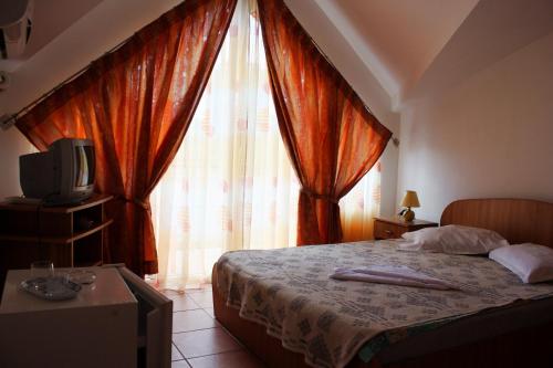 a bedroom with a bed with a television and curtains at Vila Bucura 19 A in Venus