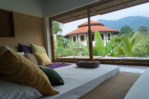a bedroom with a bed with a view of a house at Tirtha Quddus Farm Stay in Kampong Sum Sum