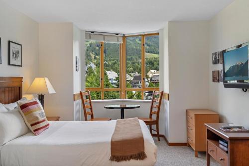 a bedroom with a bed and a table and a window at Cascade Lodge in Whistler