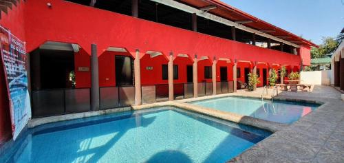 una grande piscina di fronte a un edificio rosso di Hotel La Privada a Tamasopo