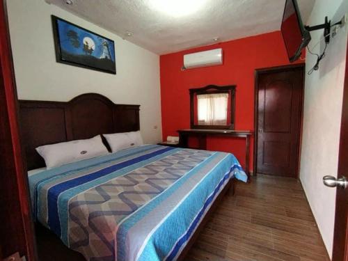 una camera da letto con un letto e una parete rossa di Hotel La Privada a Tamasopo
