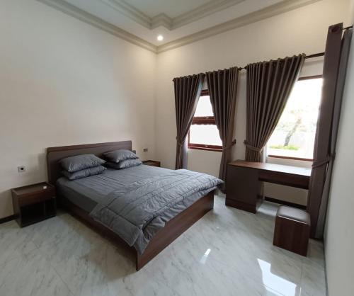 a bedroom with a bed and a desk and two windows at Dream Hills Villa in Batu