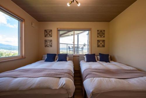 two beds in a room with a window at The Kokage in Nakafurano
