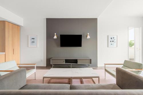 a living room with a couch and a tv on a wall at The Doyle Hotel in Charlottesville